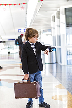 A young boy looking at his watch in airport, St Simon's Island, Georgia, United States