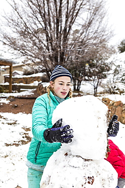 A teenage girl building a snowman, United States