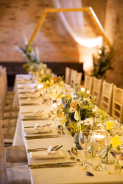 Long dining table with festive place settings for a naming ceremony in an historic barn