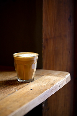 Close up of glass of cafe latte on a rustic wooden table in a cafe