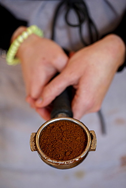 High angle close up of barista holding espresso machine portafilter