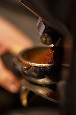 High angle close up of barista holding espresso machine portafilter