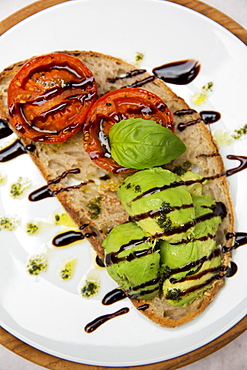 High angle close up of tomato and avocado bruschetta with balsamic vinegar reduction in a cafe