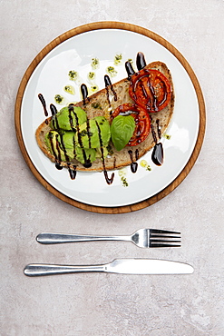 High angle close up of tomato and avocado bruschetta with balsamic vinegar reduction in a cafe