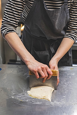 Artisan bakery making special sourdough bread, baker divind dough into loaves for baking