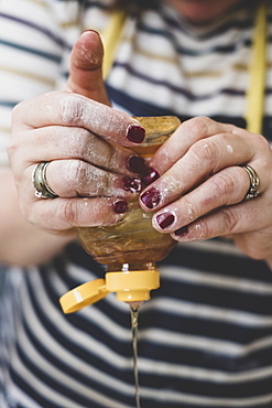 Hands squeezing honey from a plastic bottle