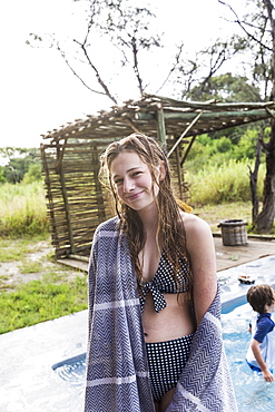 Smiling Thirteen year old girl by a swimming pool in a safari resort