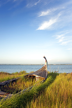 An abandoned wooden moliceiros fishing boat on the dunes overlooking the sea, Ria de Aveiro Lagoon, Portugal