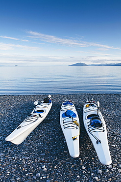 Sea kayaks on remote beach calm waters of Muir Inlet in distance, Glacier Bay National Park and Preserve, Alaska