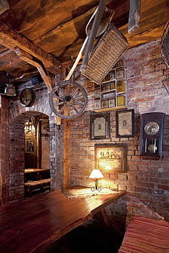 Bar with exposed brickwork and cart wheel, basket and old photographs at night, Estonia