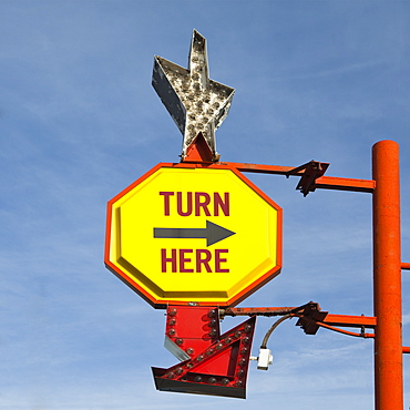 Turn Here, yellow traffic sign with arrow, on a gantry with a silver star shape, United States of America