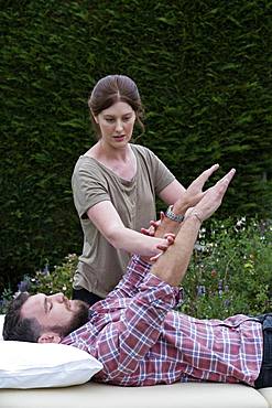 Man on a couch and therapist raising his arms in a garden therapy session