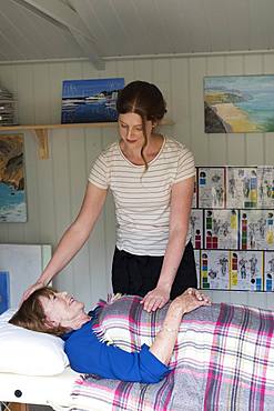 Woman on a couch a therapist placing hands on her head and stomach,