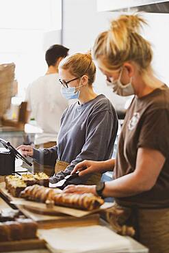 Waitress wearing face mask working in a cafe, preparing food