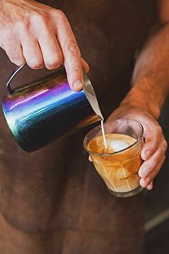 Close up of barista pouring a cafe latte