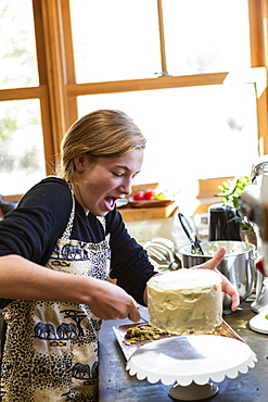 Teenage girl in a kitchen following a baking recipe on a laptop