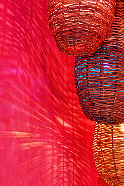 Wicker light fixtures casting shadows on red wall