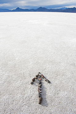 Pebbles arranged on salt flat in the shape of an arrow