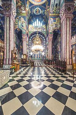 Serbian Orthodox church interior in Ljublijana, murals, painted pillars and walls, and chandelier.