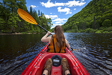 Young woman paddles down river in a kayak, Jacques-Cartier National Park, Quebec, Canada, North America