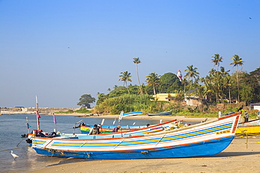 Fishing boats on beach with Tangasseri Lighthouse in background, Kollam, Kerala, India, Asia