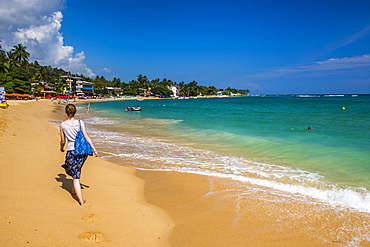 Tourist walking along Unawatuna Beach, a beautiful sandy beach on the South Coast of Sri Lanka, Asia