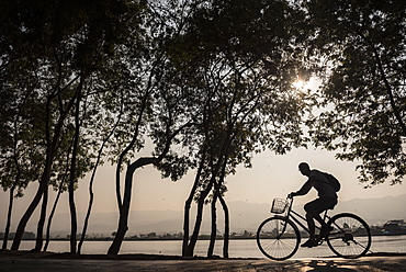 Tourist exploring Inle Lake by bicycle at sunset, Shan State, Myanmar (Burma), Asia