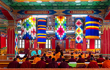 Buddhist monks worship with round gongs inside a prayer room at a monastery, Bhutan, Asia