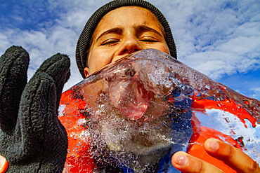 Guest from the Lindblad Expedition ship National Geographic Explorer licking ice in the Svalbard Archipelago, Norway, Arctic, Europe