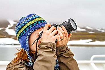 Amy Cadge, staff member from the Lindblad Expedition ship National Geographic Explorer taking a photograph with a camera in the Svalbard Archipelago, Norway, Arctic, Europe