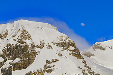 View of the nearly full moon rising over snow-covered mountains on the Antarctic Peninsula, Antarctica, Polar Regions