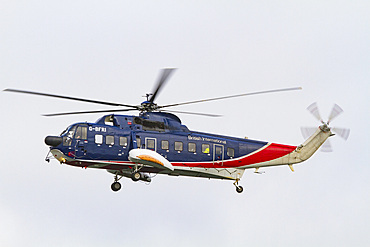 British International helicopter flying over the outer harbor of Stanley on East Island, Falkland Islands, South Atlantic Ocean.