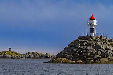 Lighthouse on the breakwall leading to the picturesque Norwegian fishing town of Reine, Lofoton Island Group, Norway.