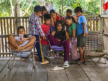 Young kids gathered around a phone watching television in the village of Amazonas, Peru.
