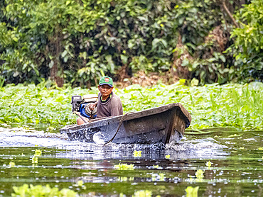 Local people in a traditional dugout wooden boat deep within the Pacaya Samiria Preserve, Peru.