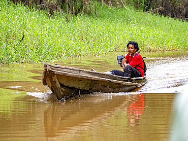 Local people in a traditional dugout wooden boat deep within the Pacaya Samiria Preserve, Peru.