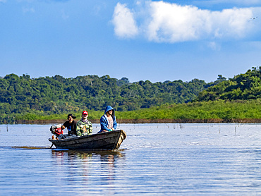 Local people in a traditional dugout wooden boat deep within the Pacaya Samiria Preserve, Peru.