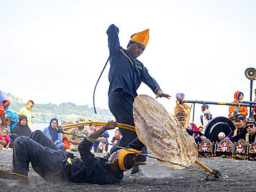Ceremonial mock fighters perform a ritualized battle with whip, shield, and bow on Sumbawa Island, Indonesia.