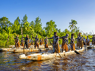 Male paddlers from the village of Per perform in a ritualistic greeting ceremony, Asmat Region, Papua, Indonesia.