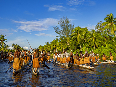 Male paddlers from the village of Per perform in a ritualistic greeting ceremony, Asmat Region, Papua, Indonesia.