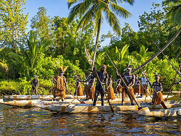 Male paddlers from the village of Per perform in a ritualistic greeting ceremony, Asmat Region, Papua, Indonesia.