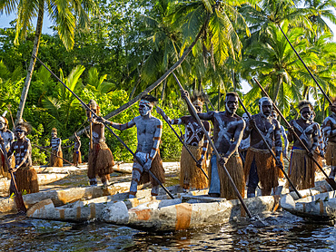 Male paddlers from the village of Per perform in a ritualistic greeting ceremony, Asmat Region, Papua, Indonesia.