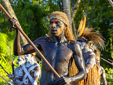 Male paddlers from the village of Per perform in a ritualistic greeting ceremony, Asmat Region, Papua, Indonesia.