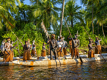 Male paddlers from the village of Per perform in a ritualistic greeting ceremony, Asmat Region, Papua, Indonesia.