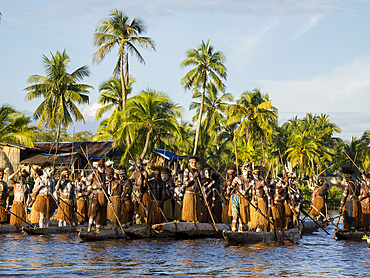Male paddlers from the village of Per perform in a ritualistic greeting ceremony, Asmat Region, Papua, Indonesia.