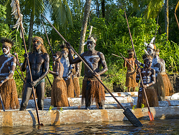 Male paddlers from the village of Per perform in a ritualistic greeting ceremony, Asmat Region, Papua, Indonesia.