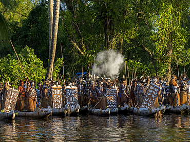 Male paddlers from the village of Per perform in a ritualistic greeting ceremony, Asmat Region, Papua, Indonesia.
