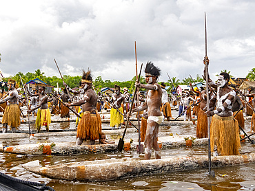 Male paddlers from the village of Uwus perform in a ritualistic greeting ceremony, Asmat Region, Papua, Indonesia.