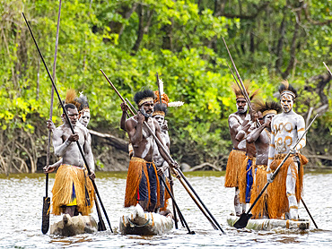 Male paddlers from the village of Uwus perform in a ritualistic greeting ceremony, Asmat Region, Papua, Indonesia.