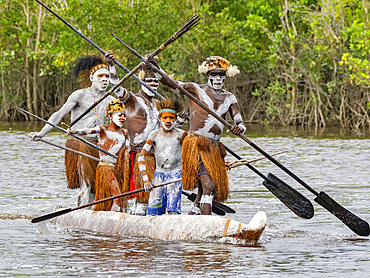 Male paddlers from the village of Uwus perform in a ritualistic greeting ceremony, Asmat Region, Papua, Indonesia.